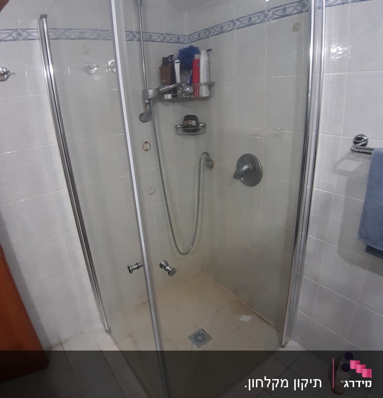 מקלחון זכוכית עם מדף מוצרים ומקלחת יד